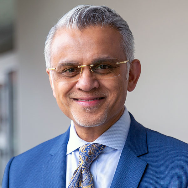 A headshot of Satchi Hiermath wearing a blue suit and tie.