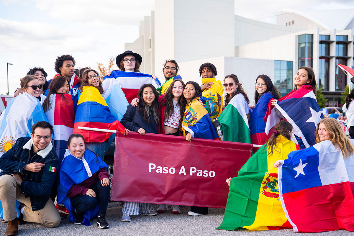 A group of students draped with various Latin flags outside Simon Skjodt Assembly Hall.