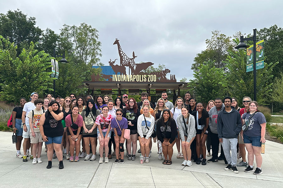 A group of students stands in front of the entrance to the Indianapolis Zoo.