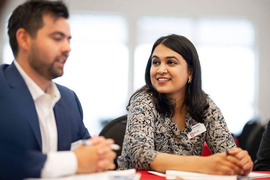 Male and female sit at a table in a meeting.