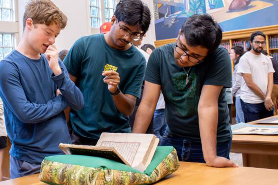 A group of male students studies a book in the Lilly LIbrary.