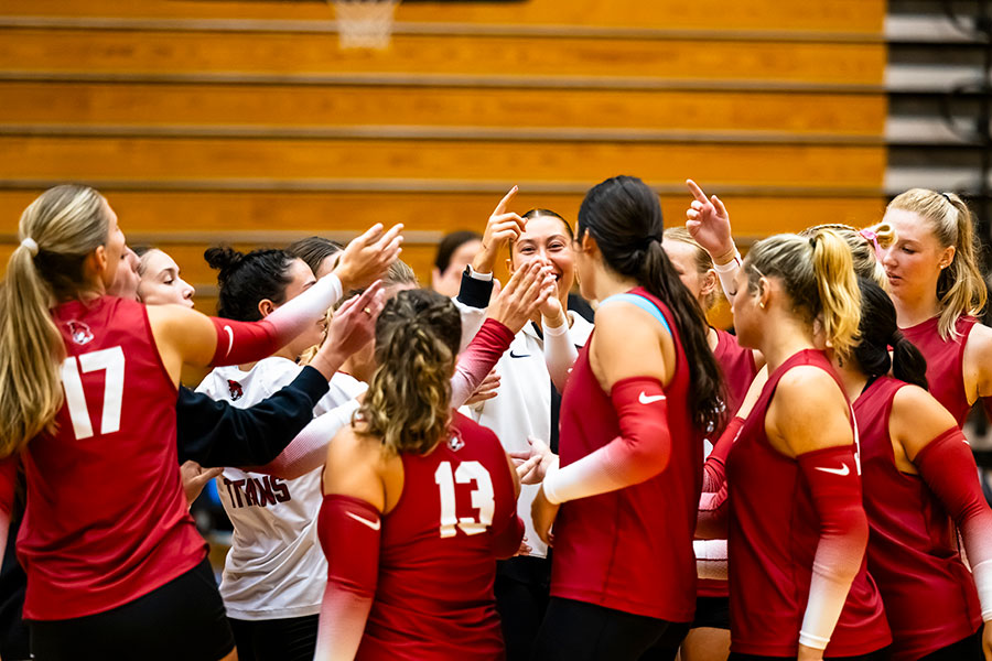 A female volleyball team gathers in a huddle.