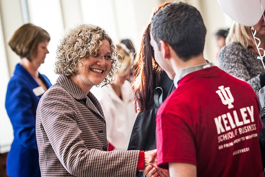 A student shakes hands with a professor.