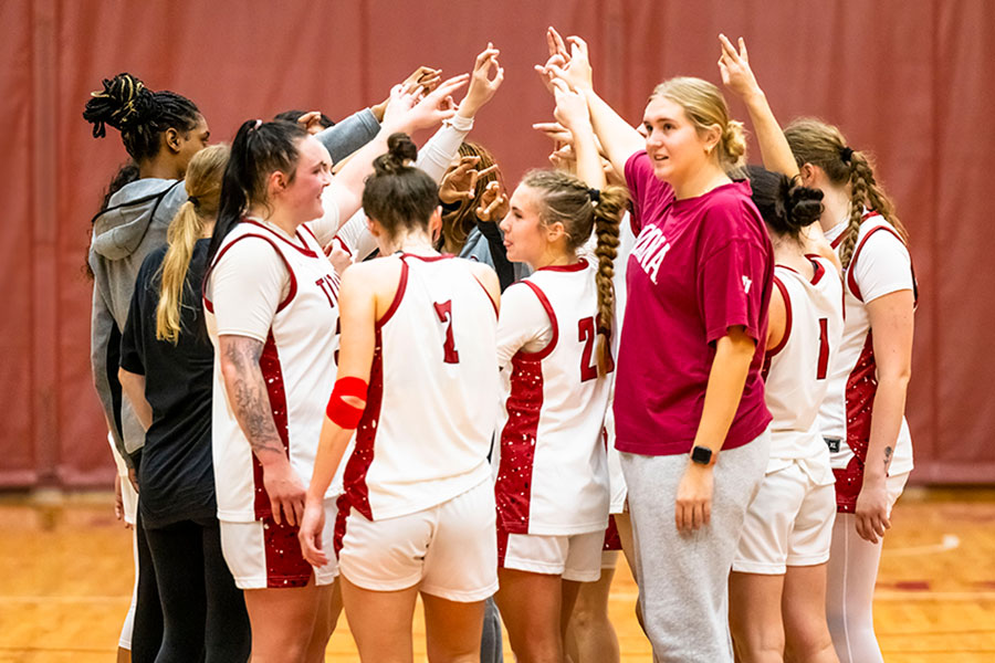 Members of the Titans Women's Basketball team raise their hands in a huddle.