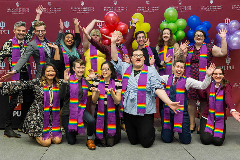 A group poses for a picture while wearing colorful scarves.