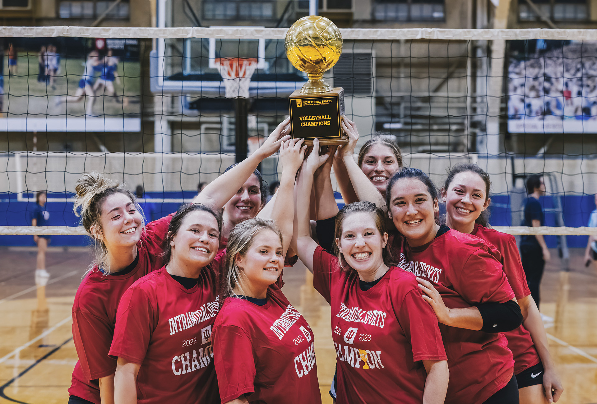 A group of students celebrates around an intramural trophy.