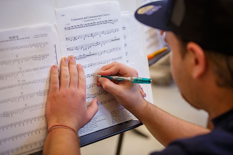 A close-up of a male student writing on sheet music.