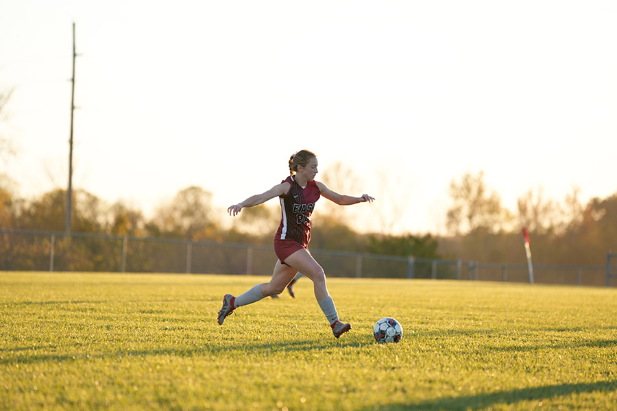 A female soccer player kicking the ball.