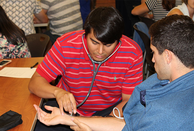 A medical student checks the pulse of a patient.