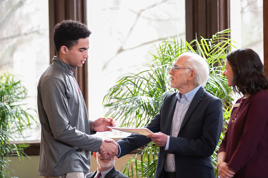A student shakes hands receiving a scholarship from the Media School.