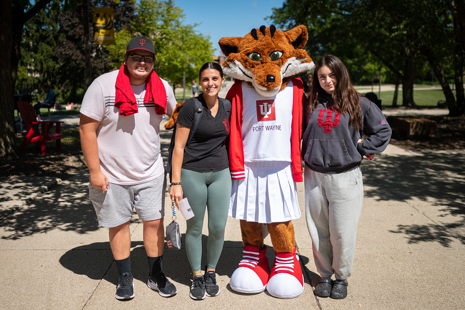 Red Fox mascot with three smiling students.