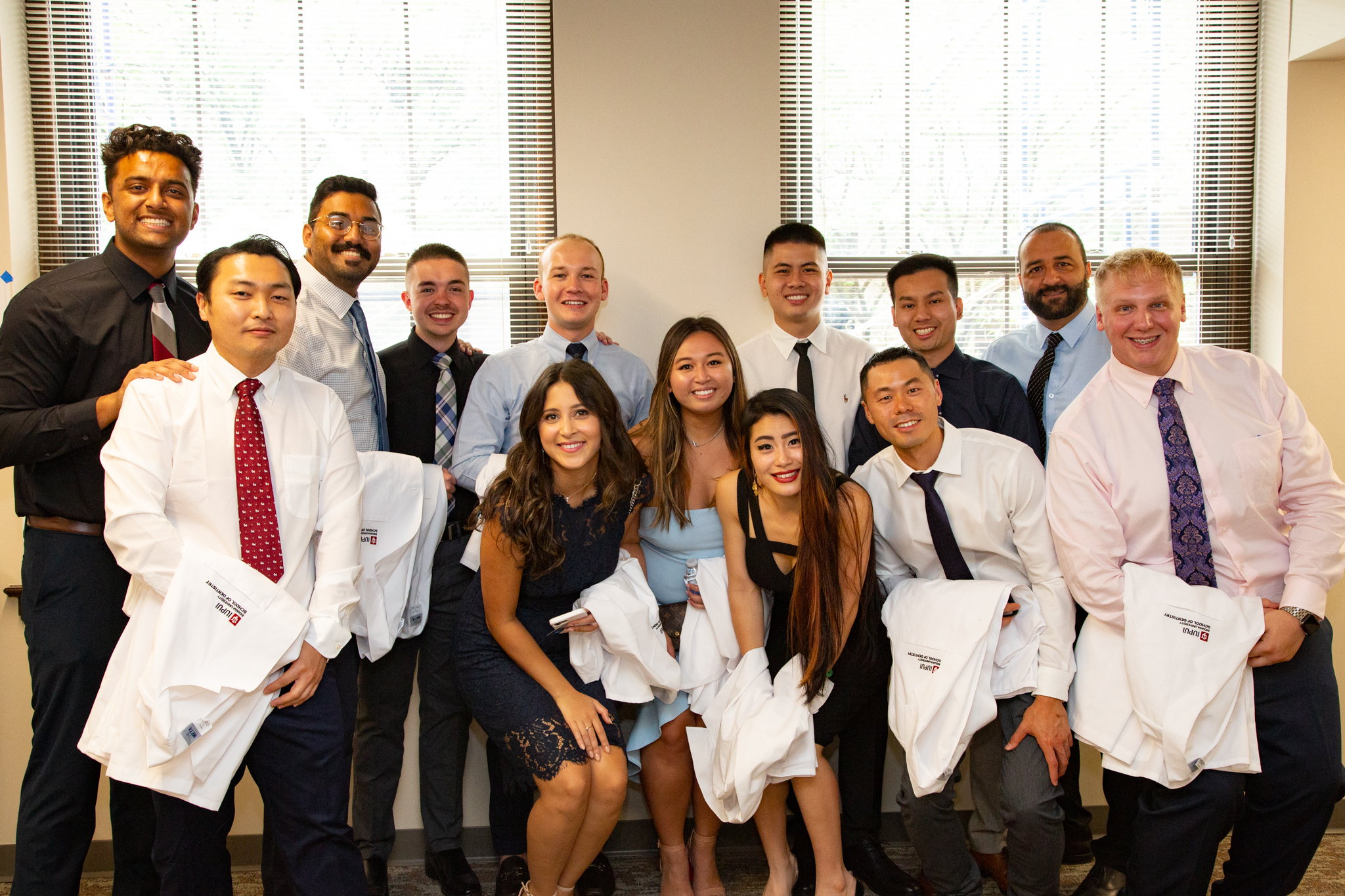 A group of IU School of Dentistry graduates holding white coats.