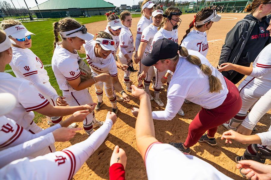 The IU South Bend softball team gathers in a huddle.