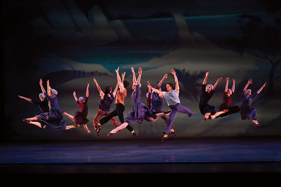 A group of ballet dancers all leaping together.