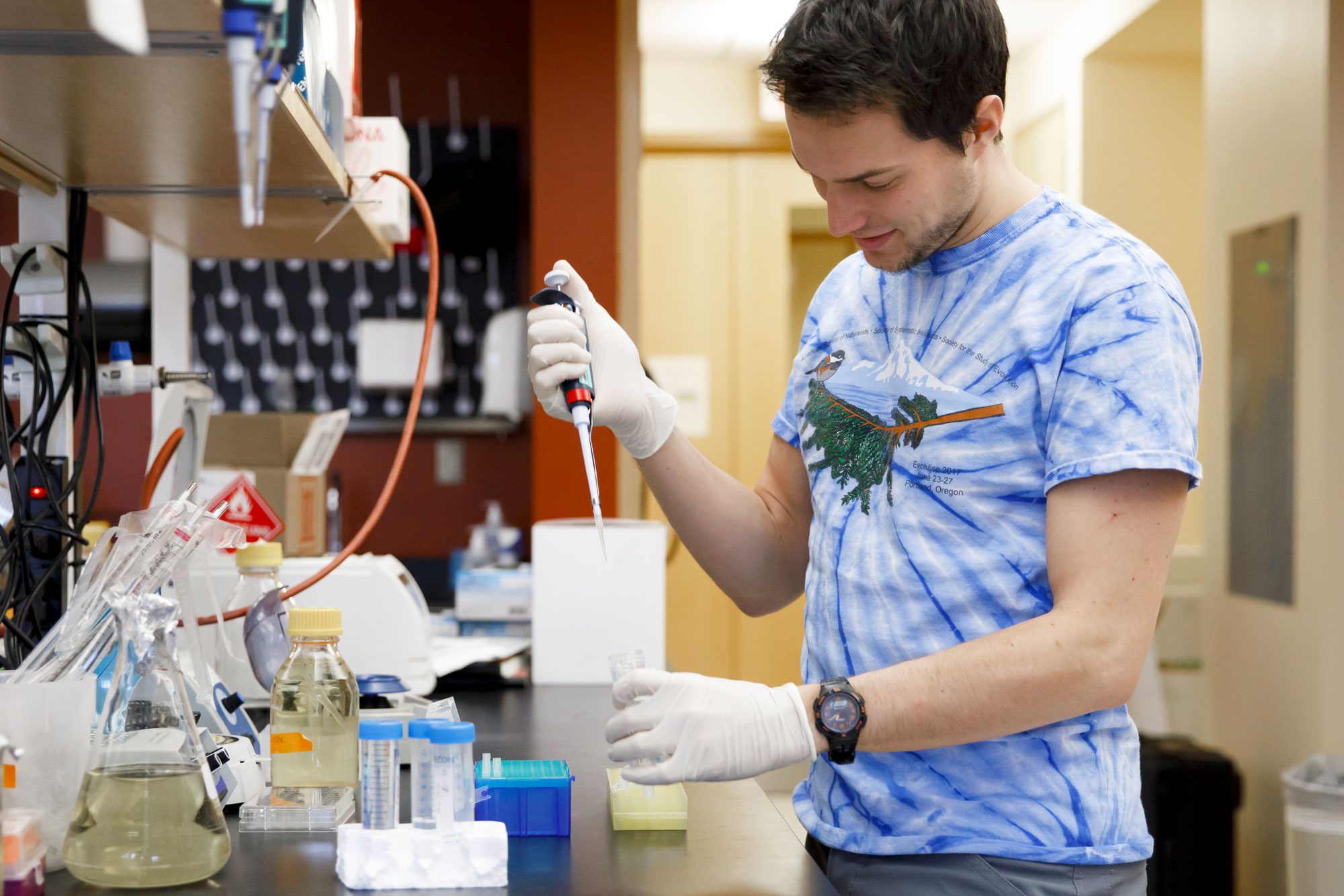 IU student in a laboratory holding a pipette and a centrifuge tube.