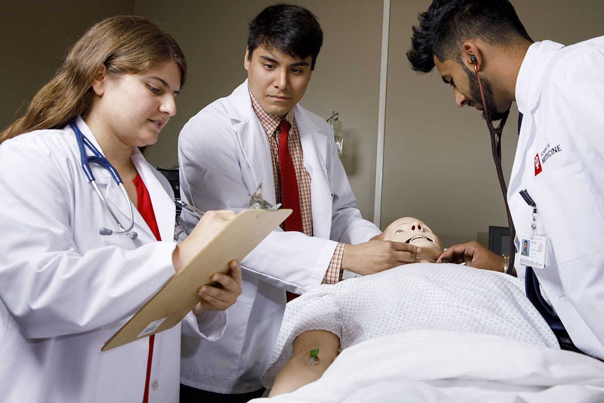 Medical students in a simulation lab perform tests on a manikin.