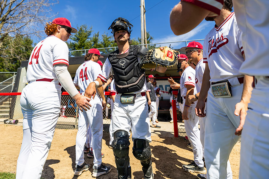 A baseball catcher walks out of the dugout as he is introduced for the game.