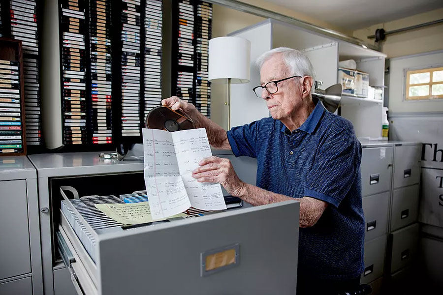 John Miley stands in a file room and looks at sports broadcasting archives.